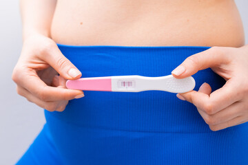 Close up woman holding a positive test near the belly. 