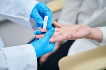 Laboratory assistant makes a finger puncture for blood sampling