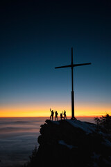 Sonnenuntergang mit Kreuz und Menschen als Silhouette beim feiern