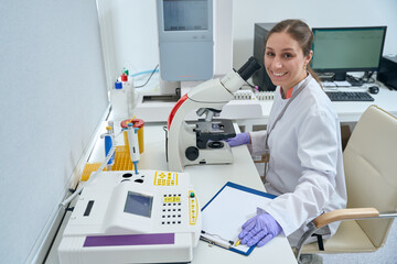 Smiling woman sits at a workplace in a laboratory