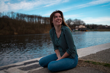 Smiling young woman enjoys in the nature by the lake.