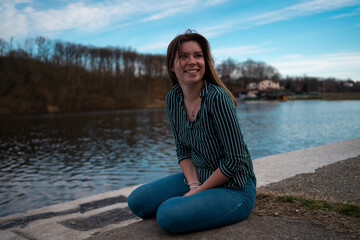 Smiling young woman enjoys in the nature by the lake.