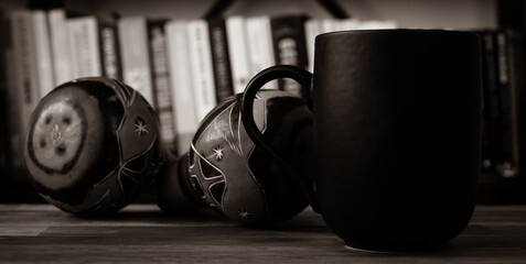 Cup of coffee and rumba shaker on the table with bookcase background.Latin music and coffee concept 