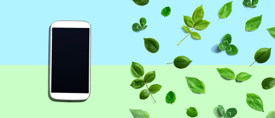 White smartphone with green leaves - flat lay