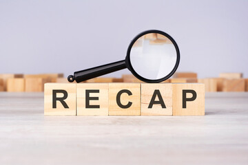 wooden blocks with a magnifying glass text: RECAP