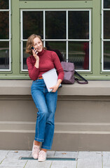 a young girl back to school, stands with a backpack and talks on the phone