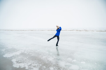Caucasian woman in a blue sweater skating on a frozen lake. 