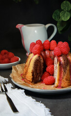 close up of home made marble cake with raspberries on top, dark grey background 