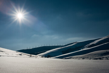 Wind farm along the horizon in snow.

