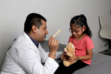 Latino pediatrician doctor checks his girl patient with autism spectrum disorder ASD, he...