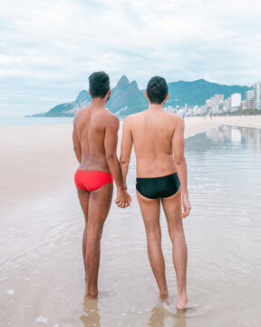 gay couple holding hands on the beach in brazil