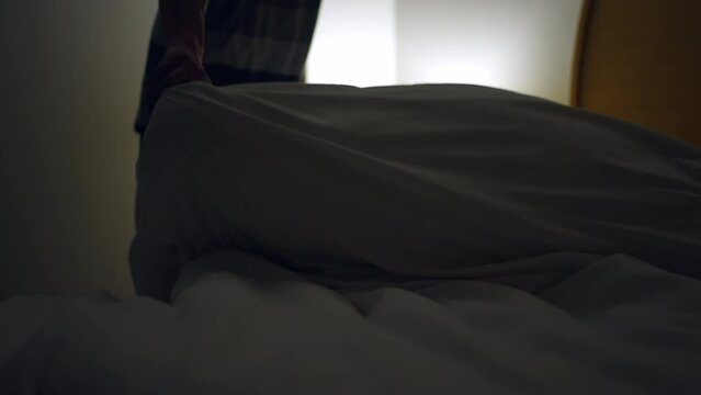 Person going to bed and sleep. Man lays down and turns off light besides bedside