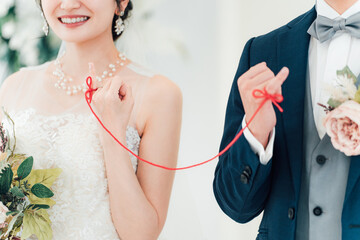 結婚式場で赤い糸で結ばれる新郎新婦（ブライダル・ウェディング）
