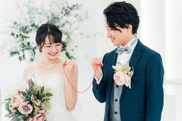 結婚式場で赤い糸で結ばれる新郎新婦（ブライダル・ウェディング）
