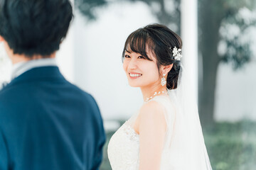 結婚式場でブーケを持って見つめ合う新郎新婦(ウェディング・ブライダル・夫婦)
