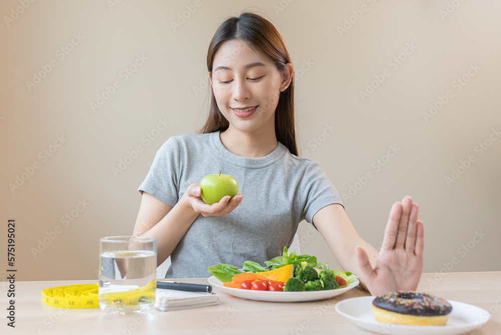 Wall mural woman on dieting for good health concept. close up female using hand push out her favourite donut an