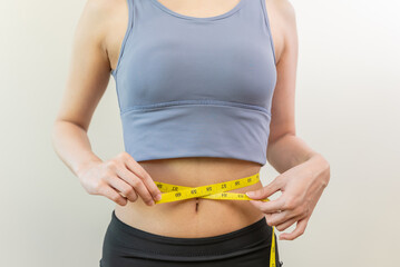 Young slim woman measuring her waist by measure tape after a diet