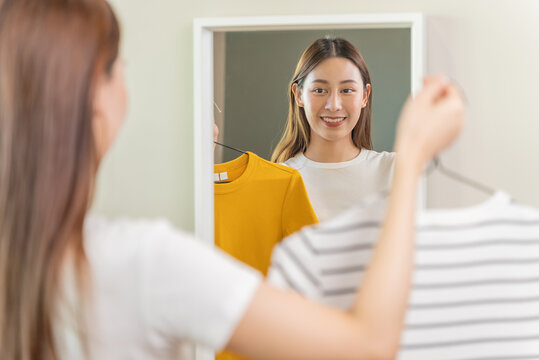 Young woman try a shirt looking in mirror in shop