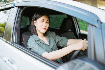 Close up portrait of pleasant looking female with glad positive expression, being satisfied with unforgettable journey by car, sits on driver`s seat, enjoys music. People, driving, transport concept