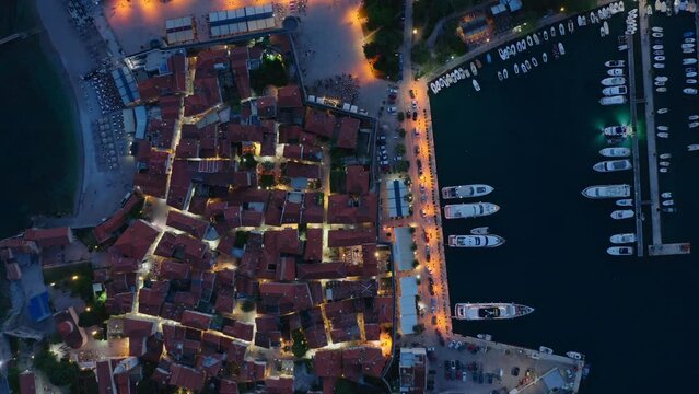Top down aerial view illumination in budva old town. Evening time with a lights in the street. Summer season. 
