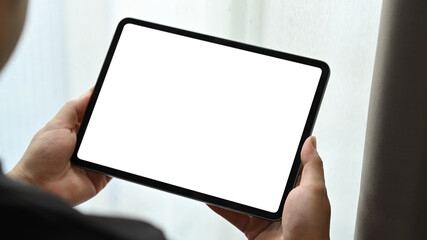 Close up view of man hands holding mock up digital tablet. White empty screen for text information...