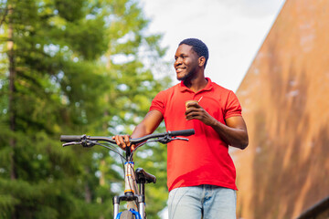 latin amerixan man in casual clothes smiling while leaning on his bike