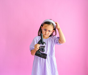 Pretty little girl holding a compound microscope in her hands while scratching her head in confusion. - Powered by Adobe