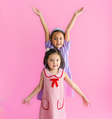 Two pretty little girls standing and reaching up high and low.