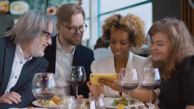 Group of mixed race people using phones in restaurant. Realtime