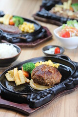 Japanese Hamburg steak with brown sauce and vegetables on a black hot plate in a Japanese restaurant