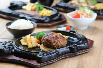 Japanese Hamburg steak with brown sauce and vegetables on a black hot plate in a Japanese restaurant