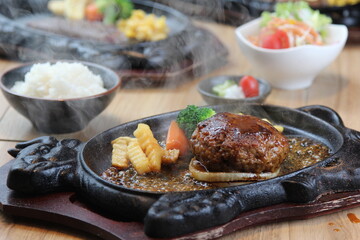 Japanese Hamburg steak with brown sauce and vegetables on a black hot plate in a Japanese restaurant
