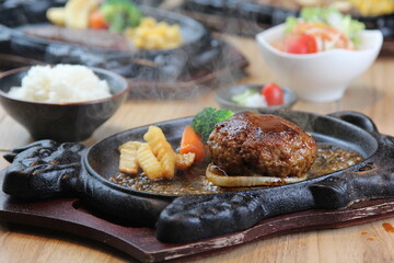 Japanese Hamburg steak with brown sauce and vegetables on a black hot plate in a Japanese restaurant