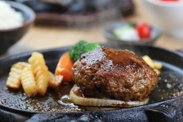 Japanese Hamburg steak with brown sauce and vegetables on a black hot plate in a Japanese restaurant