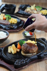 Japanese Hamburg steak with brown sauce and vegetables on a black hot plate in a Japanese restaurant