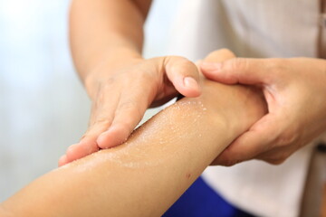 Obraz na płótnie Canvas Masseur applying apricot kernel scrub to exfoliate skin of of young woman