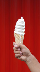 A person holding a bright red ice cream cone, its sweet frozen treat the perfect summertime dessert.