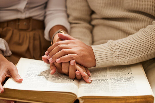 Closeup, hands and couple with bible, praying and support with love, spiritual and religious practice. Zoom, hand and man with woman, prayer and scripture for faith, trust and wellness with bonding
