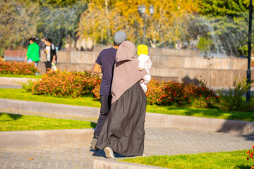 Muslim family spend time together in the park. Girl in a hijab. Romantic Muslim couple in love with a baby in their arms.