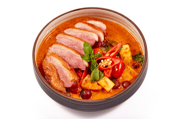 Red curry with roasted duck isolated on white background, this food contains such as red curry paste, chili, tomato and pineapple.