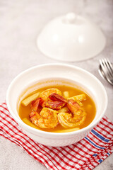 Sour soup with lotus stem and shrimps in a white bowl on table. local food of Thailand.