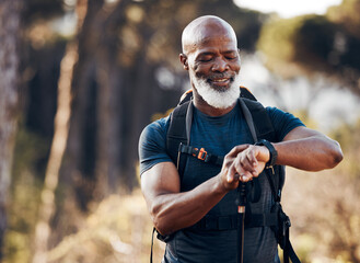 Hiking, man and watch for time in nature forest trekking for fitness and cardio exercise. Senior black person smile while walking outdoor with backpack and smartwatch for travel, health and wellness