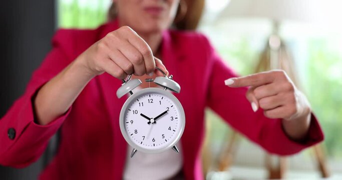 Businesswoman holding alarm clock pointing finger