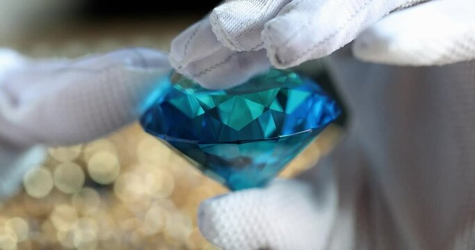Hand holds brilliant or diamond gemstone in blue color