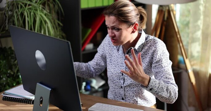 Angry business woman screaming into computer monitor at workplace