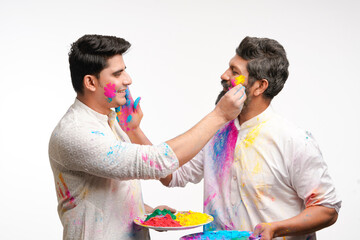 Two indian man applying color to each other and celebrating holi festival.