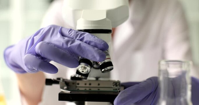 Closeup of scientist hand adjusting fixation and adjustment of microscope and objective eyepiece