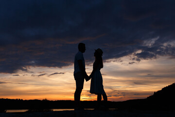 Couple standing holding hands at summer sunset