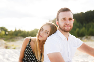 Fototapeta premium couple in love laughing sitting on sandy beach on vacation