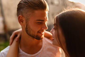 man and  young woman embrace in rays of setting sun in the city